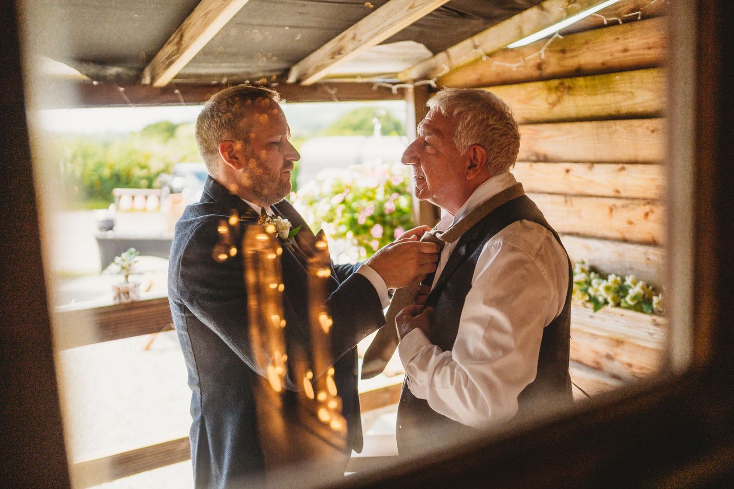 Two elderly people share an intimate conversation in a rustic wooden setting.