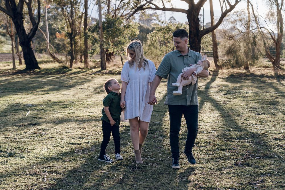Family walking together through sun-dappled woodland setting.