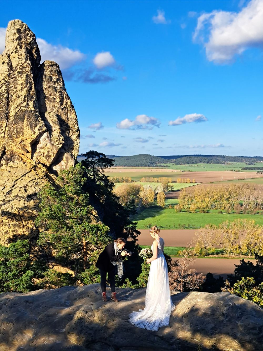 Fotografin aus Braunschweig fotografiert eine Braut auf einem Berg im Harz bei Sonneschein und blauen Himmel.