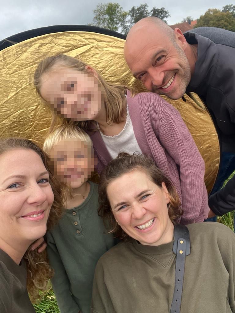 Fotografin lachend mit einer Familien vor einem Reflektor nach einem Familienshooting in Gifhorn.