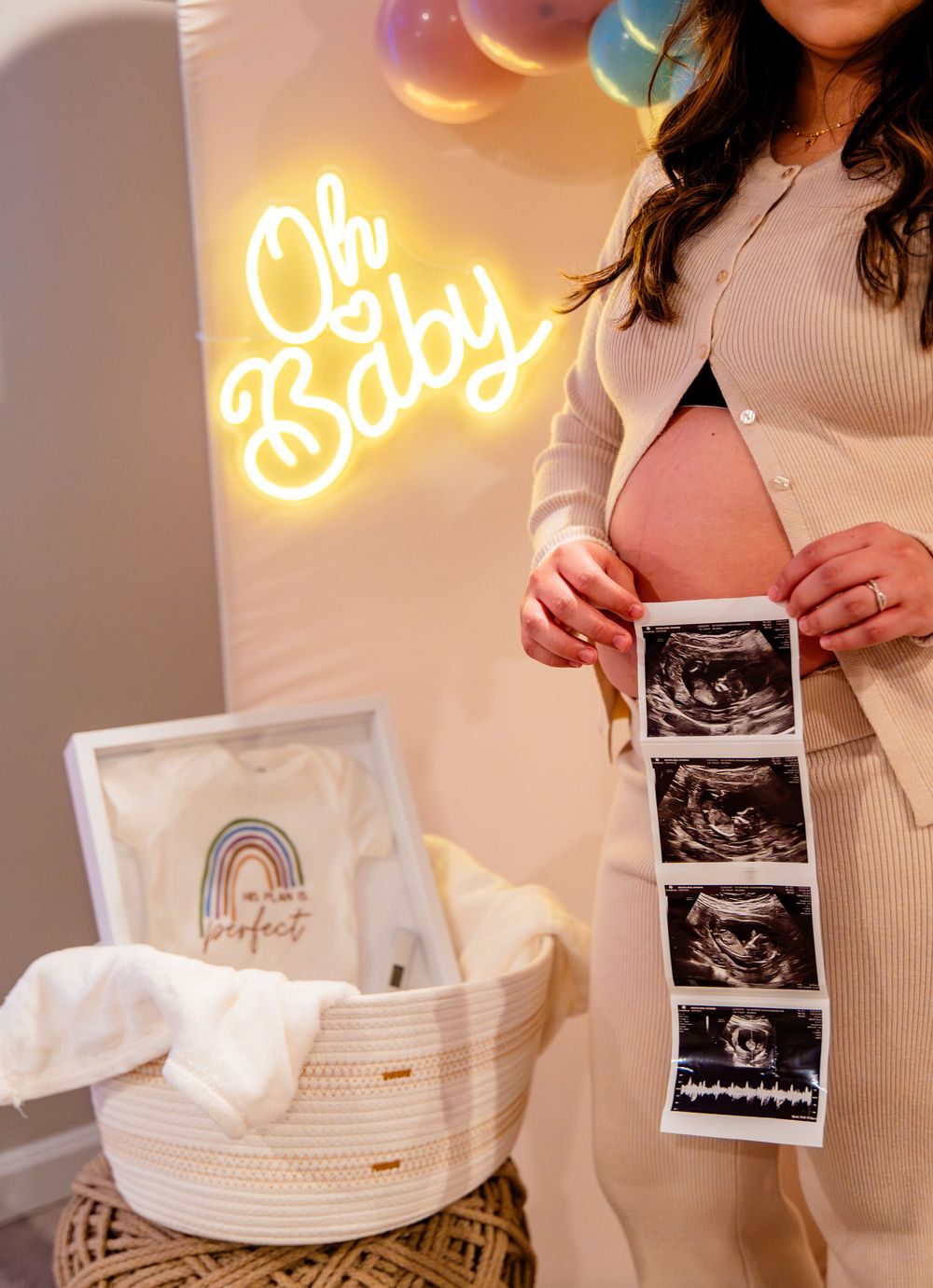 A series of ultrasound photos displayed next to a white baby bassinet with neon signs glowing in the background.