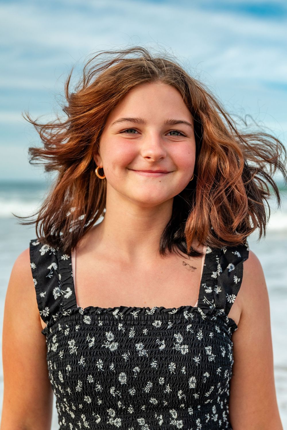 Summer beach portrait with ocean waves and blue sky in background.
