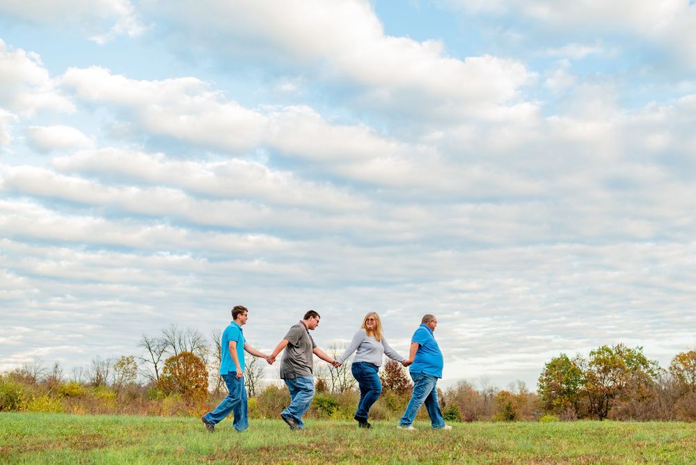 Family members lined up in a row against a cloudy sky during a casual outdoor photo session.