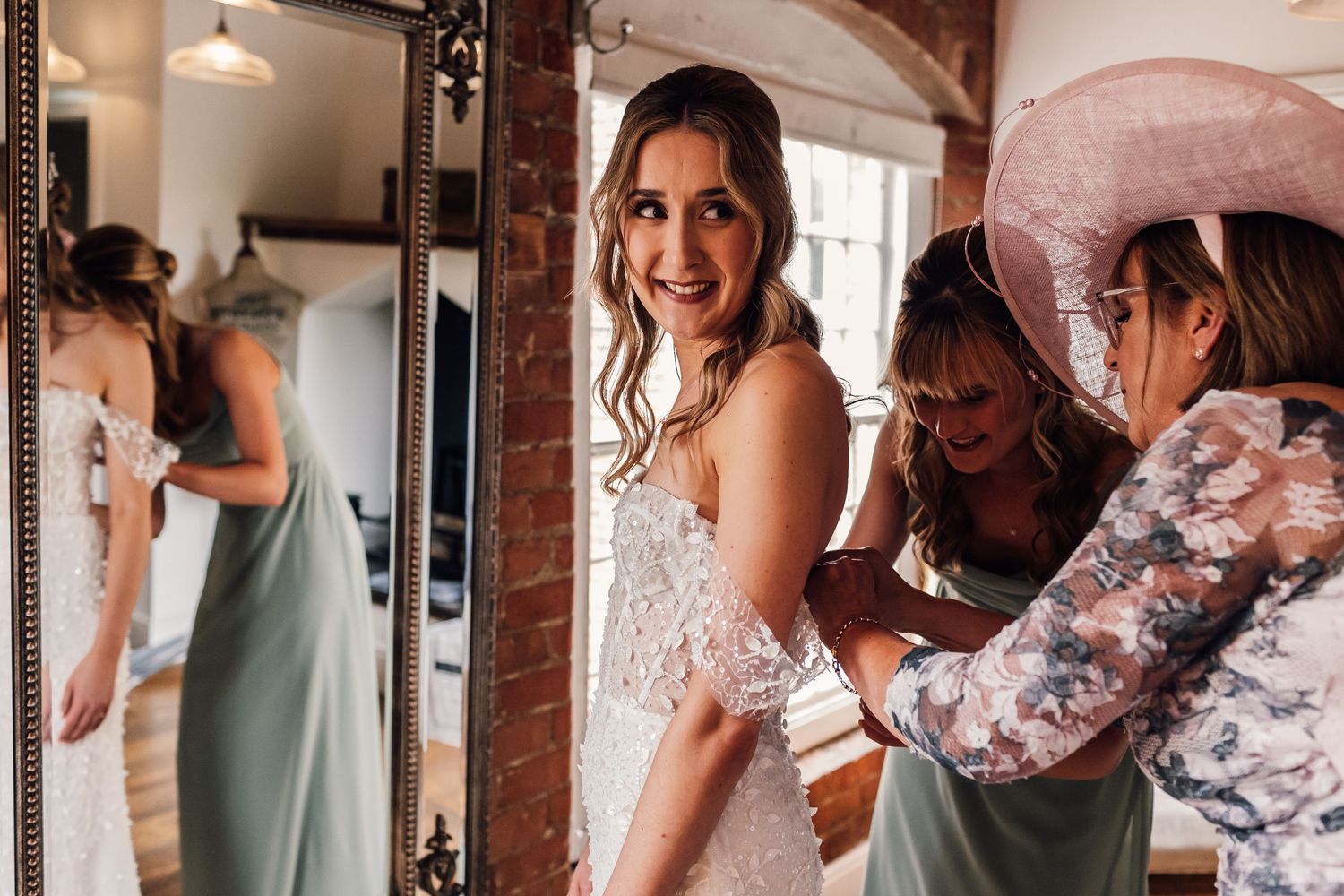 Getting ready moment captured in rustic brick room with natural window light.