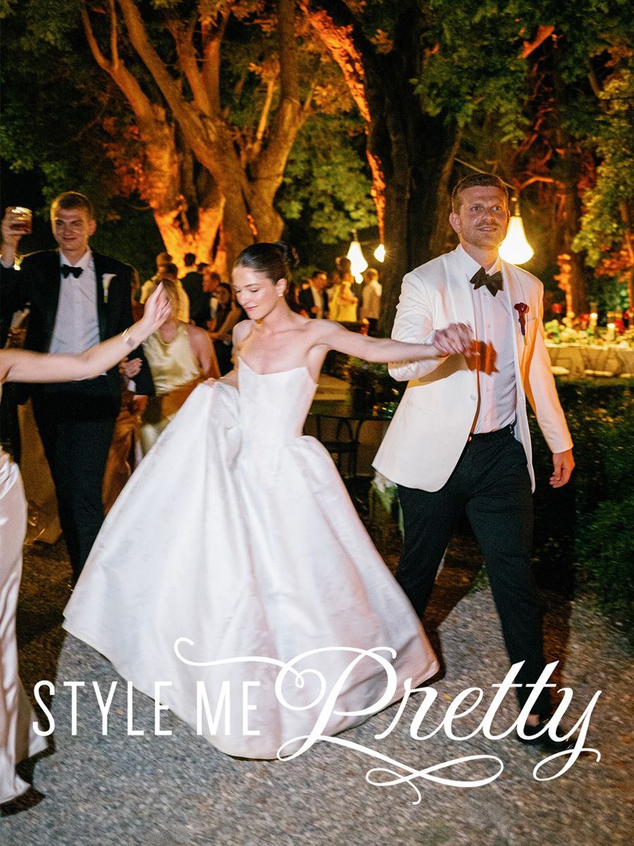 Bride in white ball gown dances with groom in white tuxedo jacket at elegant outdoor wedding reception at Borgo Stomennano, Tuscany, Italy.