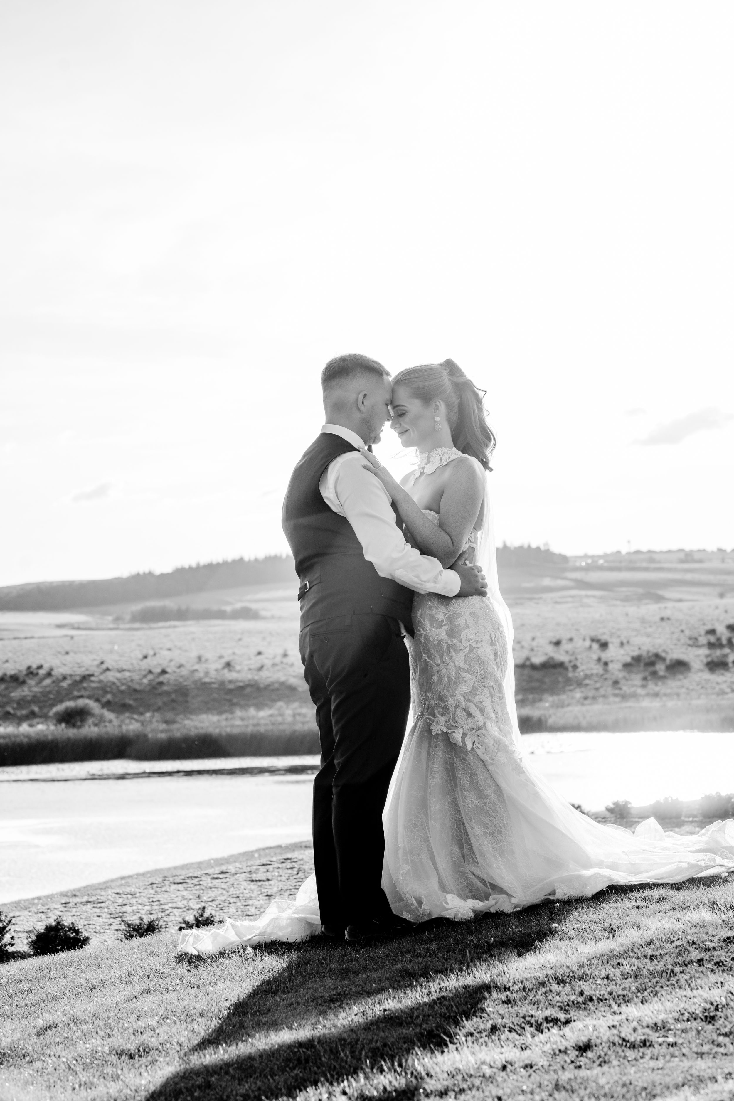 A romantic black and white wedding photo sequence shows a couple sitting together on a hilltop overlooking a scenic vista.
