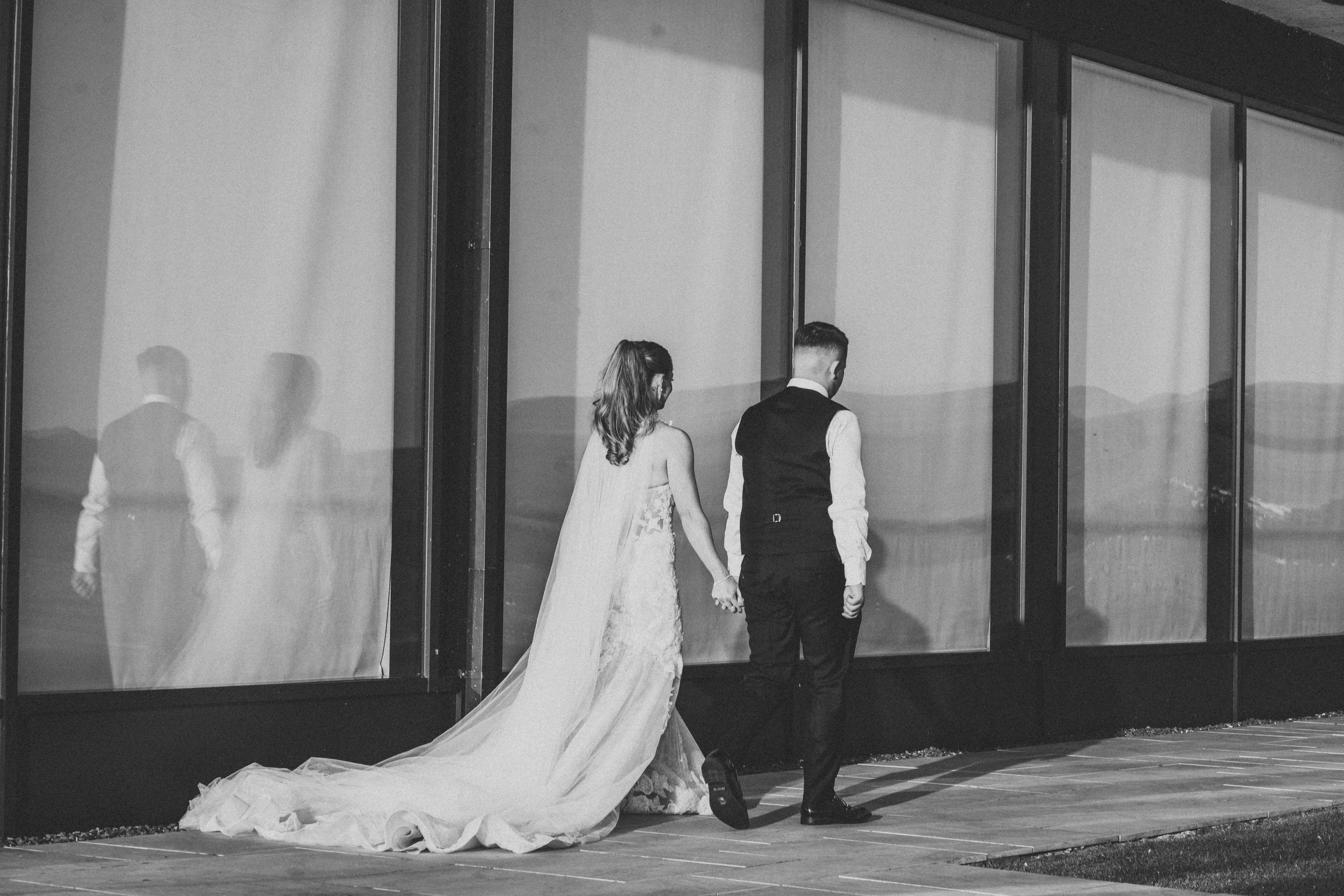 Black and white image of silhouettes against glass windows creating reflective shadows in a modern building interior.