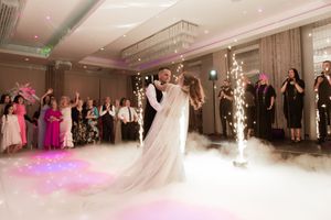 Couple performing their first dance on a fog-covered dance floor at an elegant wedding reception.