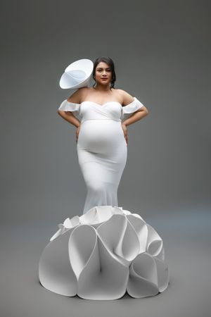 A modern mermaid-style white wedding dress features dramatic ruffled details at the bottom and an off-shoulder neckline.