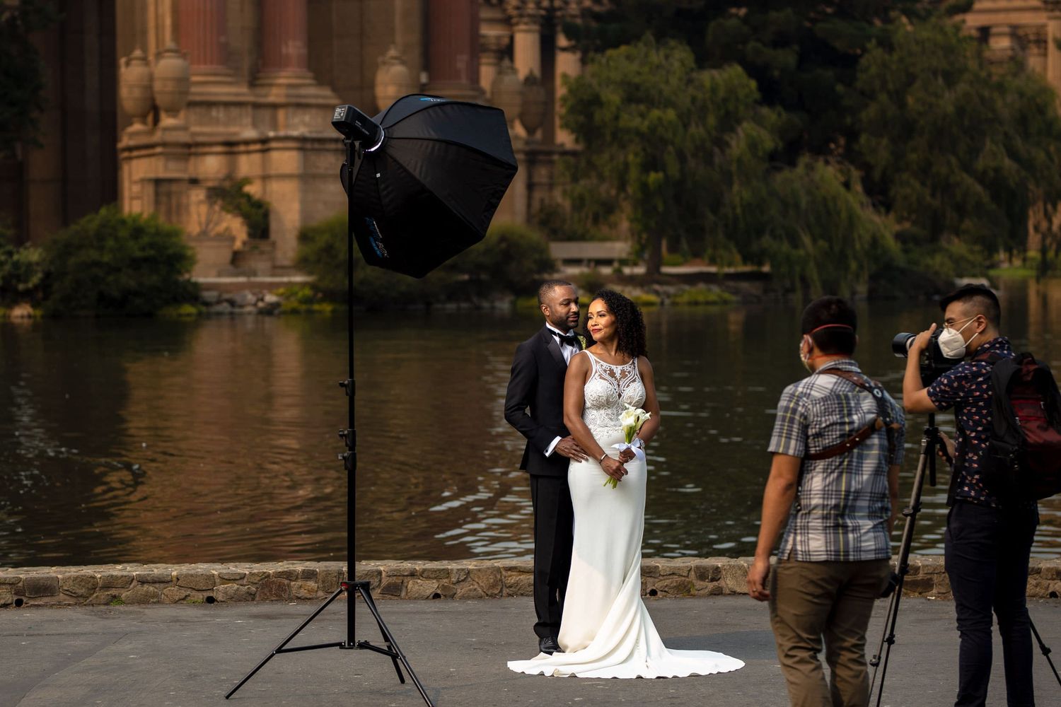 A bride and a groom during a wedding photoshoot by the lake a wedding photographer and an assistant capturing the moment