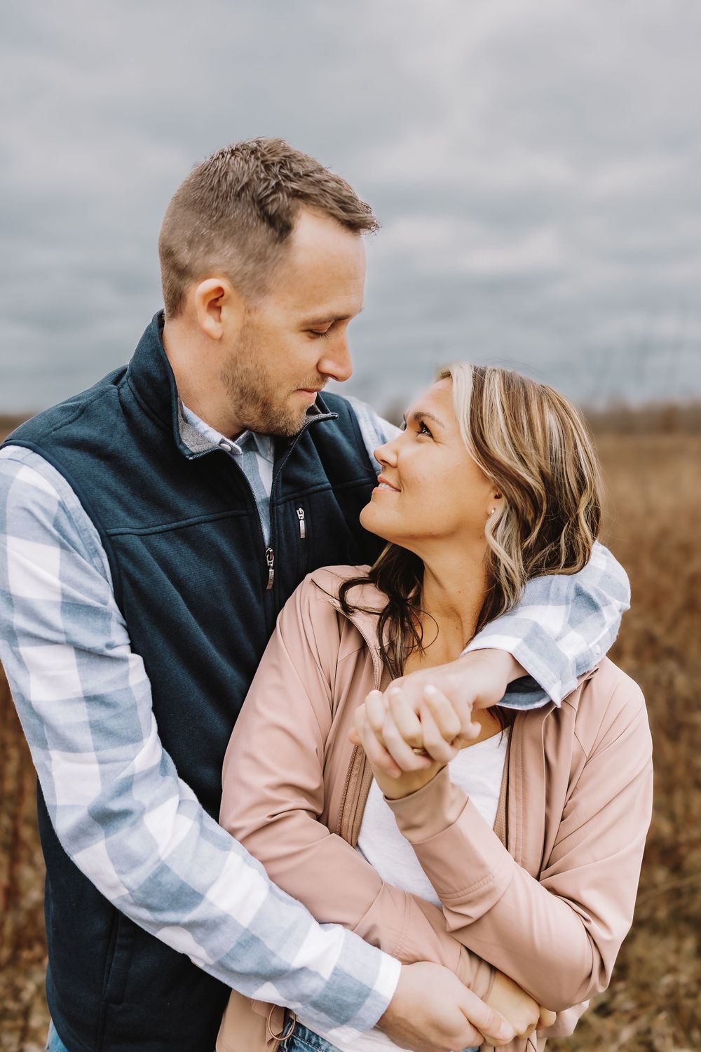 A couple embraces and shares intimate moments in a rural field during a romantic autumn photoshoot.