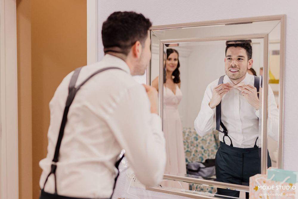 A wedding photographer captures a reflection in a mirror while taking photos during preparation for the ceremony.