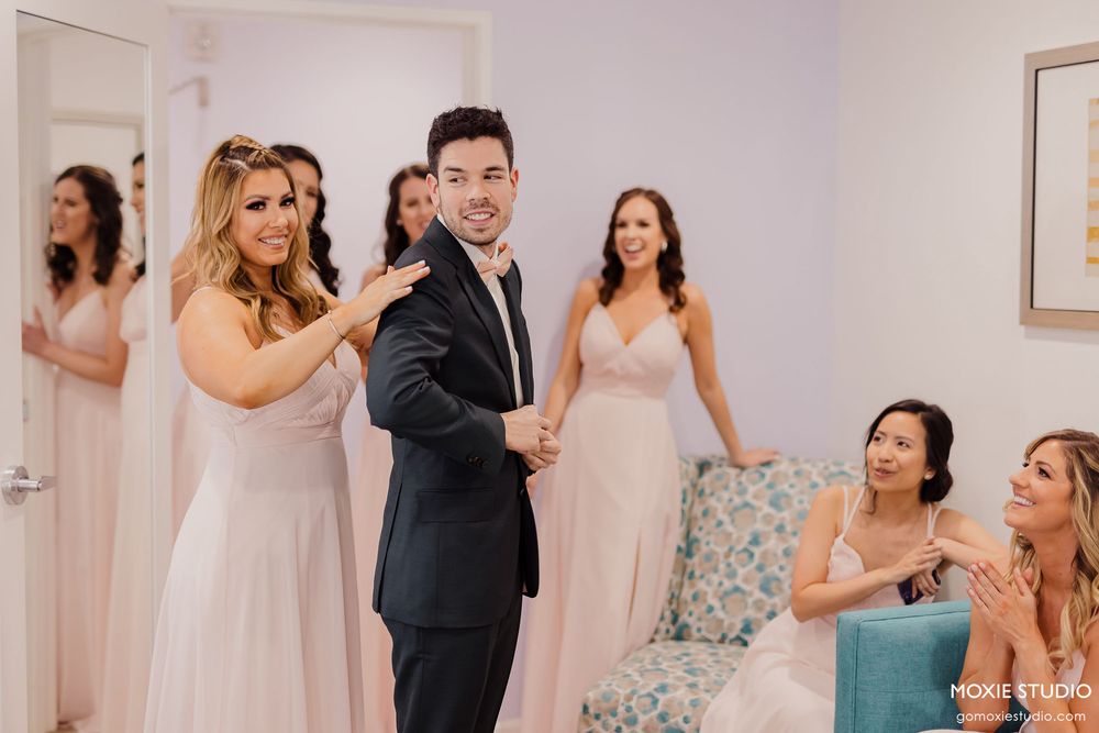Wedding celebration scene with people in formal attire dancing and enjoying festivities in a bright indoor venue.