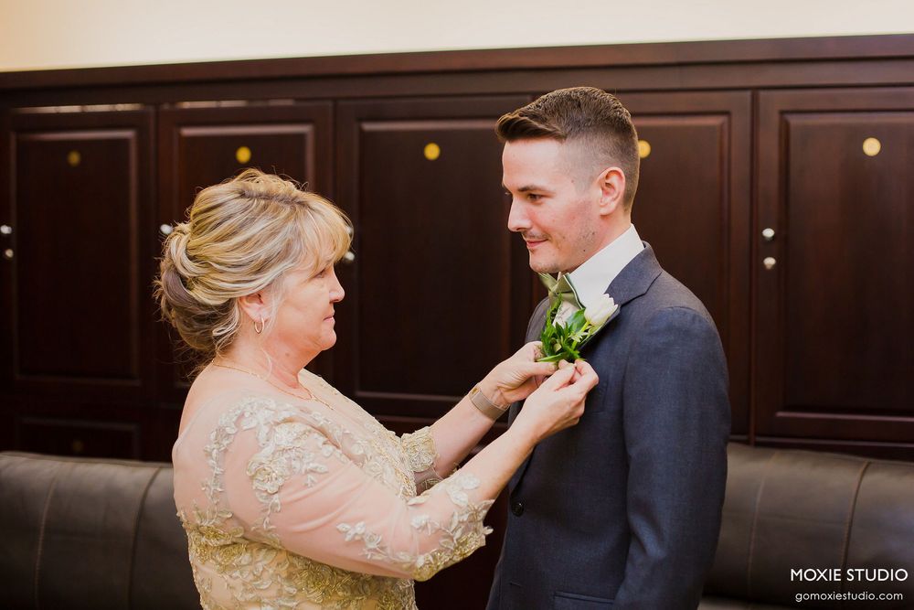 Wedding party members dancing and celebrating in an elegant venue with dark wood paneling and ambient lighting.