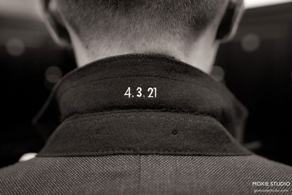 Black and white close-up photo showing the back of a person's neck with the numbers 4.3.21 embroidered on their collar.