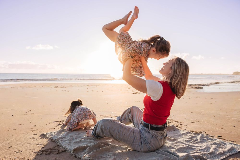 Playful moment at sunset on a beach with a red top and jeans against golden light.