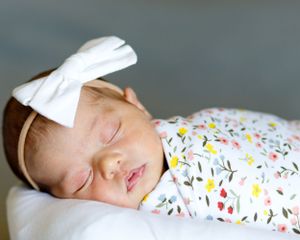 newborn baby girl peacefully sleeping in a cozy swaddle during in-home newborn session