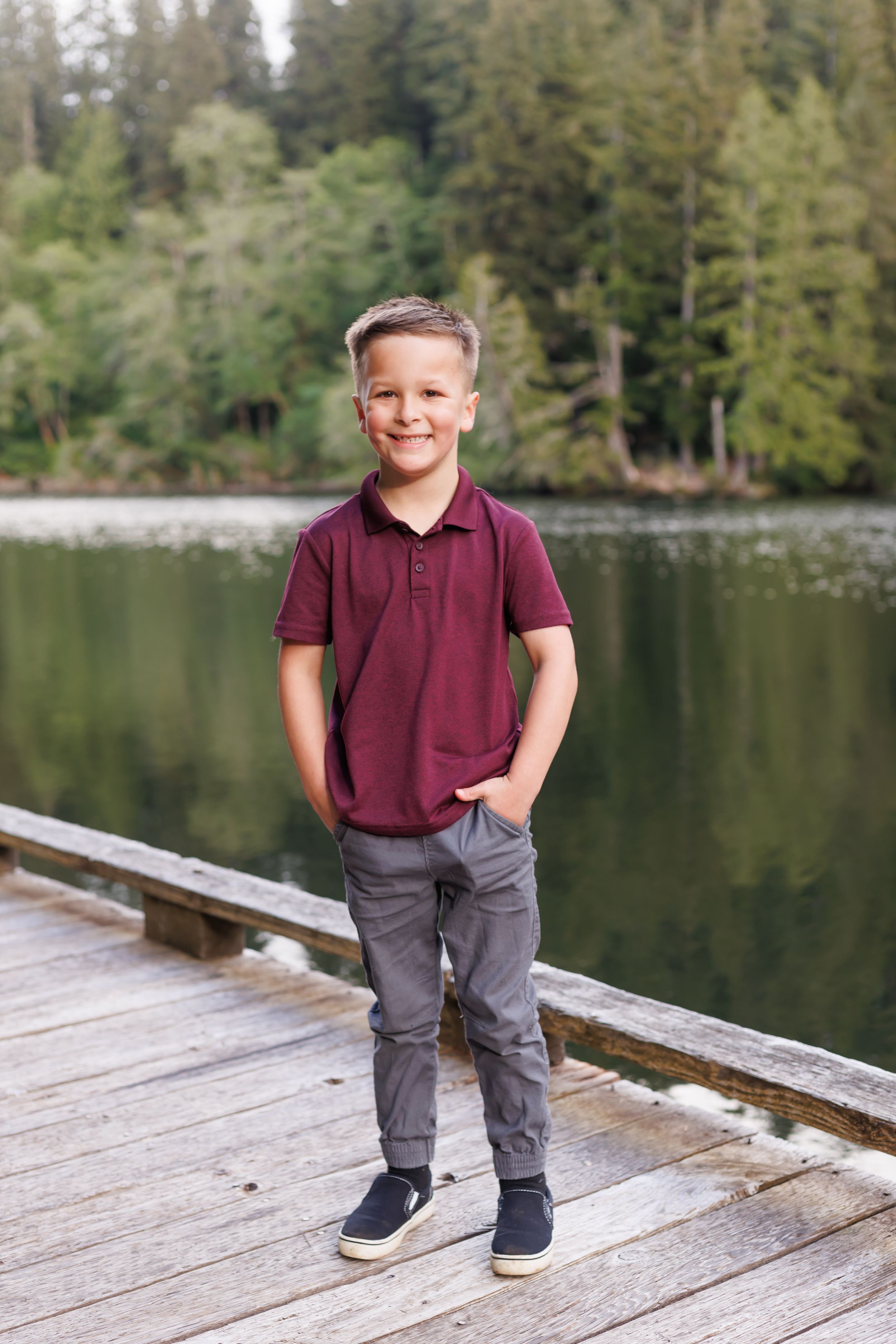 energetic boy posing by a beautiful lake