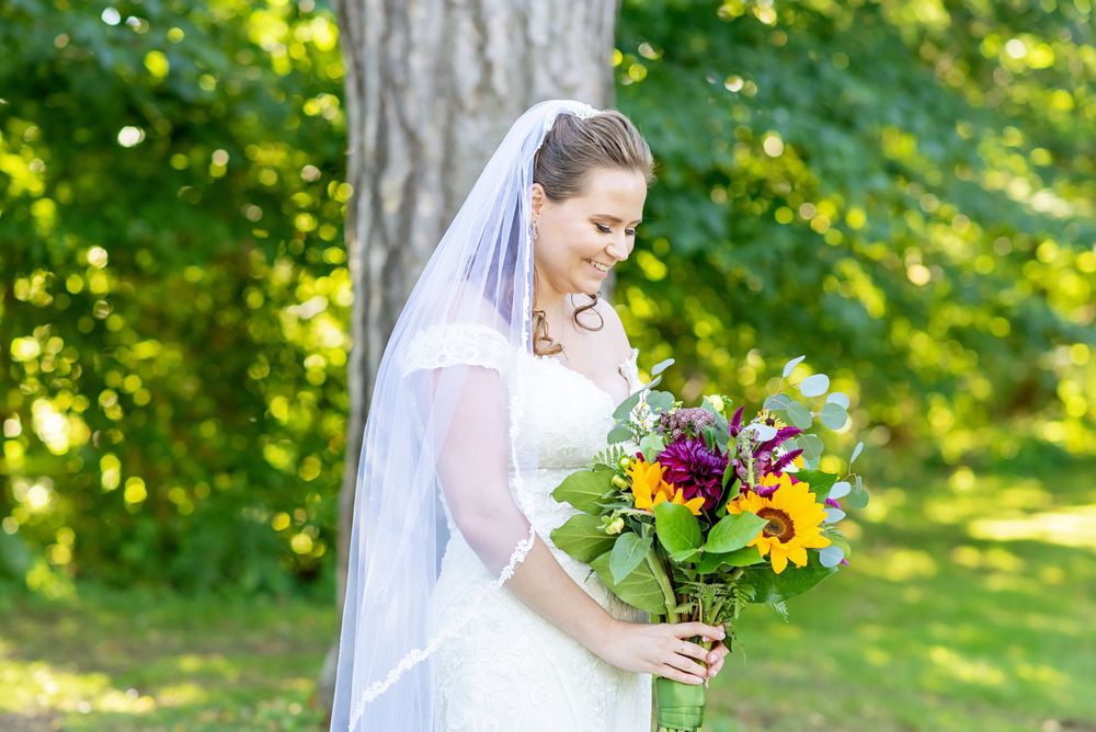 Bride holding vibrant sunflower and wildflower bouquet in outdoor garden setting at Elsie Perrin Williams Estate in London.