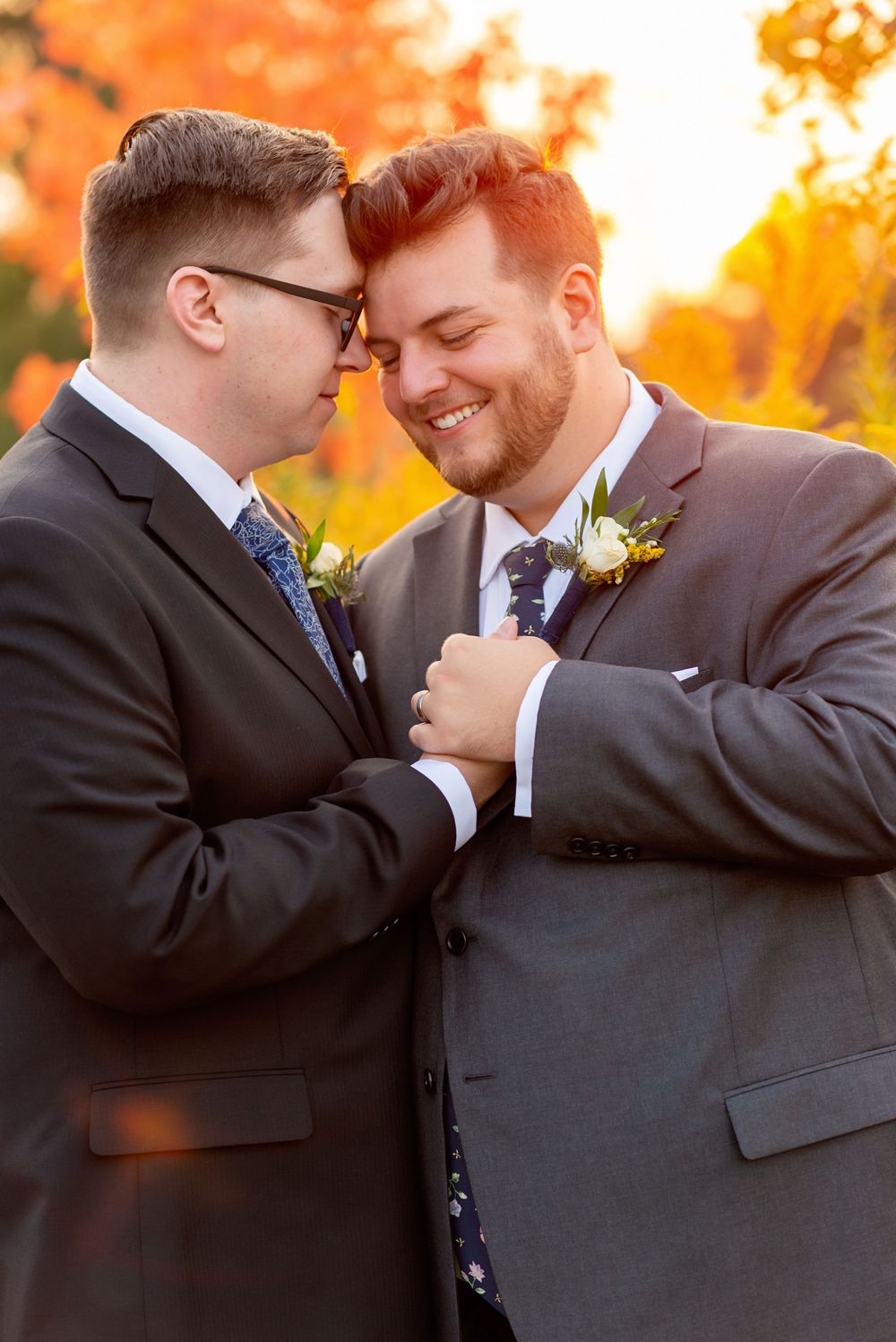 Intimate moment captured between two people in dark suits against a backdrop of warm autumn colors in Waterloo at Canadian Clay & Glass Gall