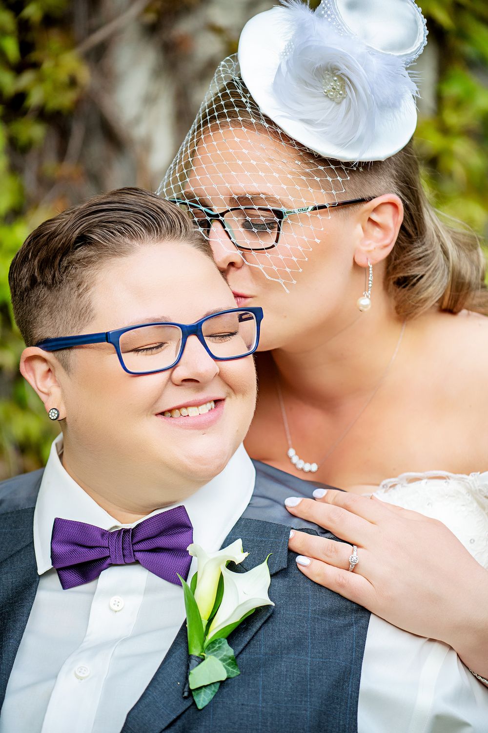 Wedding couple in formal attire with white fascinator and purple bowtie at the Old Court House in London.