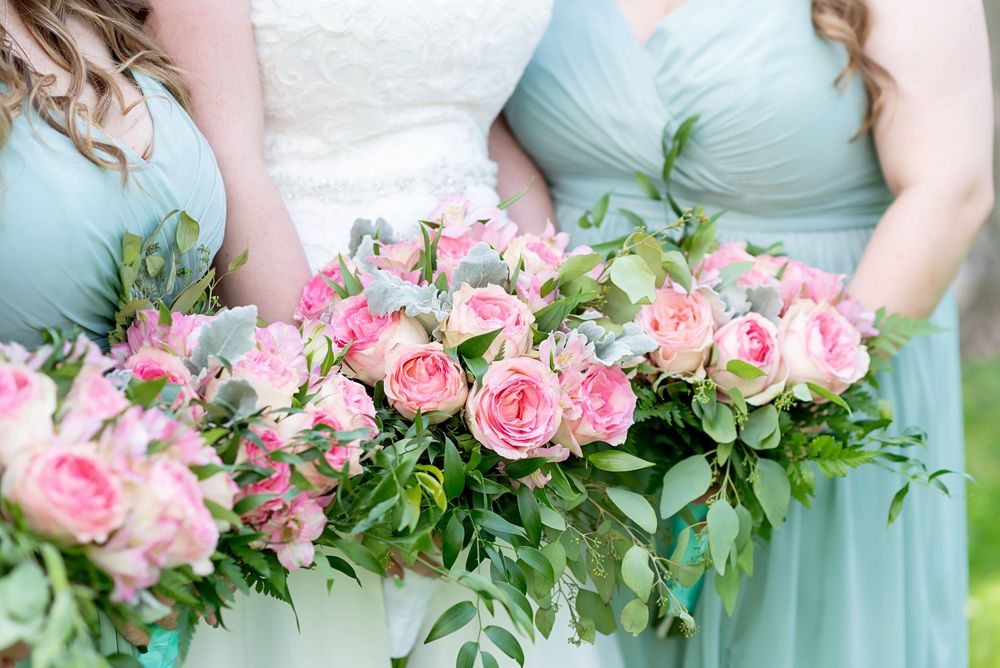 Pink and white floral bouquets held against mint green bridesmaid dresses at Elsie Perrin Williams Estate in London.