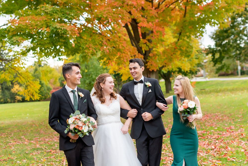Wedding party laughing together under autumn trees with colourful fall foliage at McKillop Park in London Ontario.