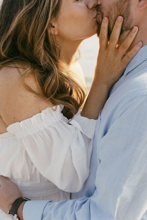 Close-up shots of a couple embracing and sharing moments in matching white and light blue attire in engagement photography in Hunting Island
