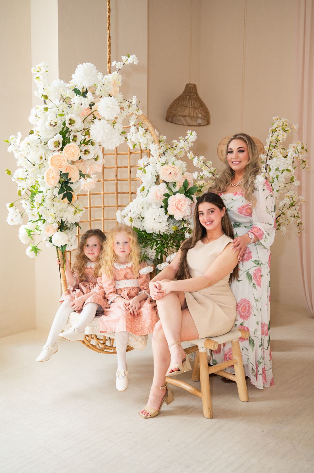 Elegant floral-themed studio portrait with soft pink and white decor, featuring feminine spring fashion and beautiful blooms.