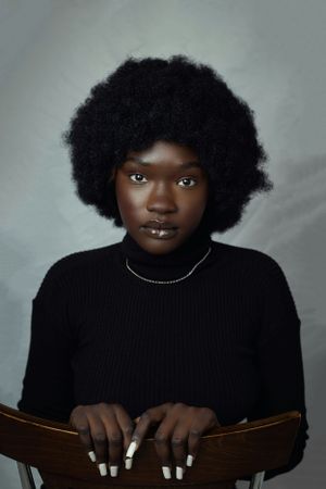Studio portrait with natural afro hairstyle wearing black turtleneck and delicate necklace.