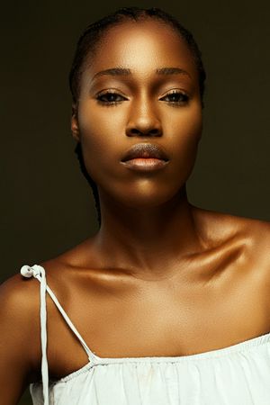 Professional beauty portrait with warm golden lighting and white off-shoulder top.