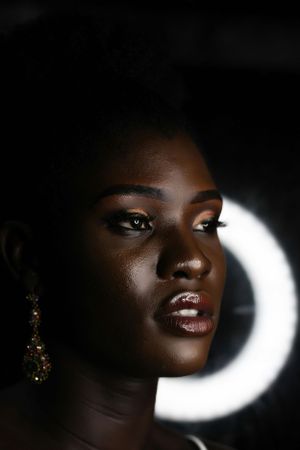 Artistic portrait with dramatic lighting featuring a glowing crescent moon shape in the background.