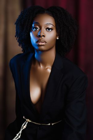 Fashion portrait with natural hair and blazer under dramatic blue lighting.
