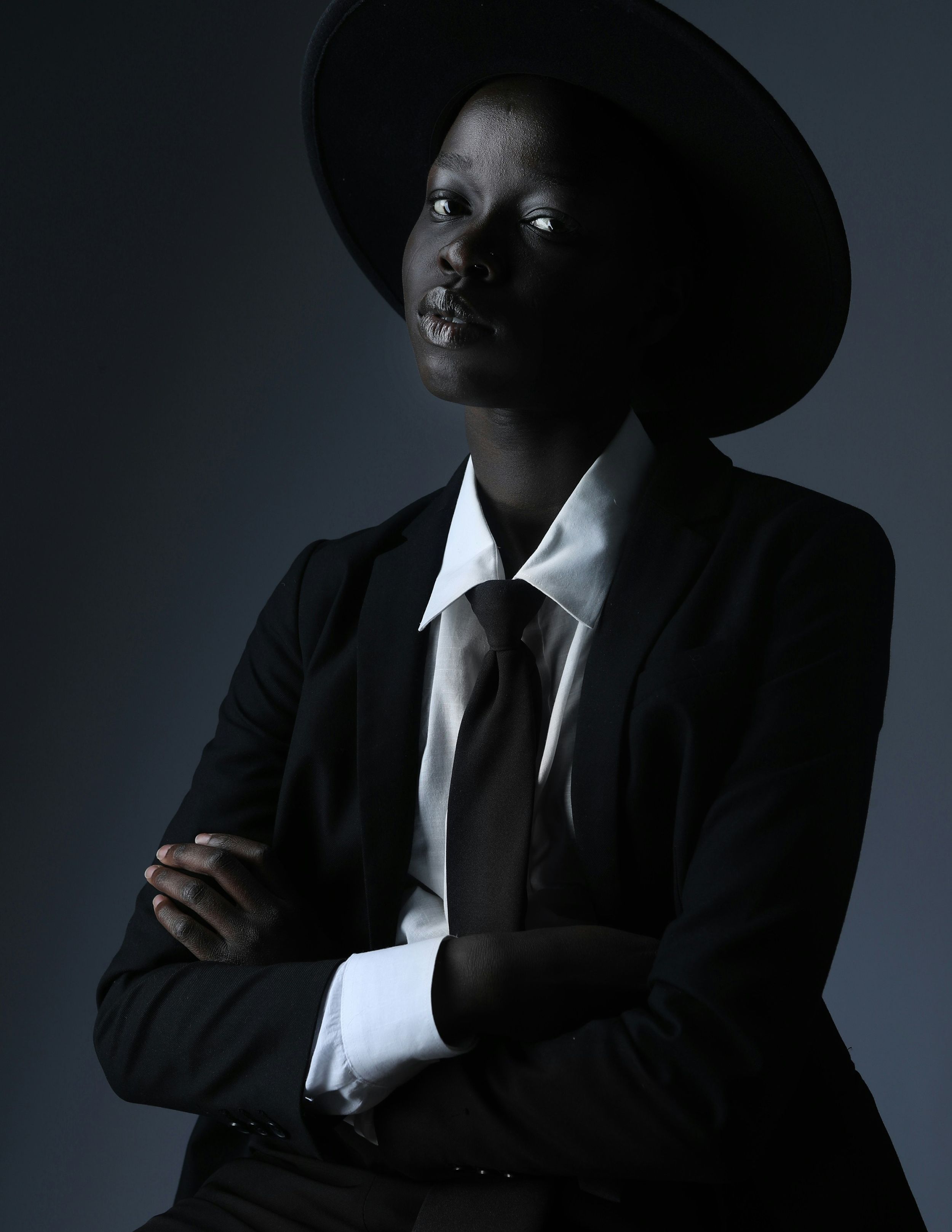Dramatic low-key portrait in black suit, white shirt and wide-brimmed hat.
