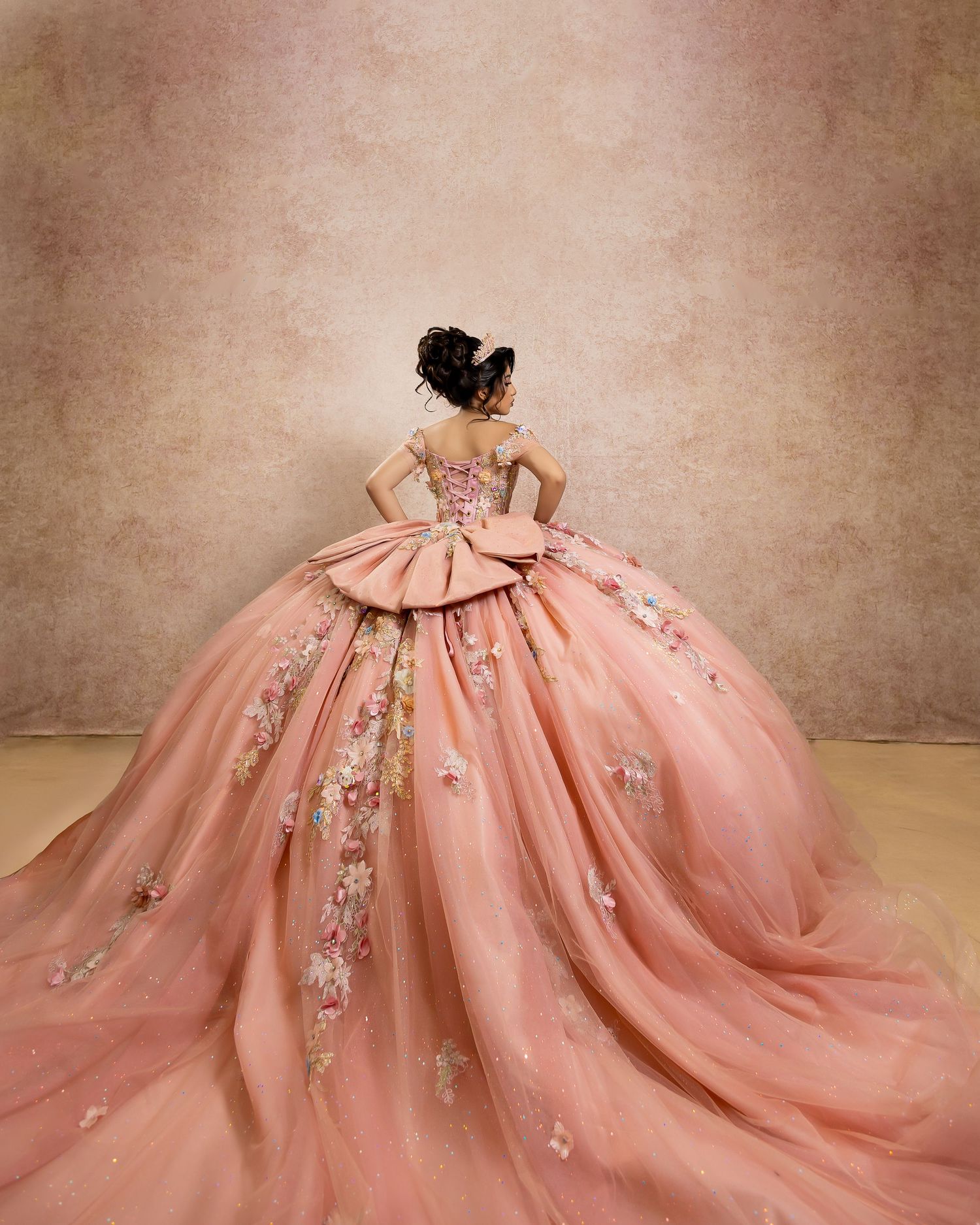 Elegant peach ball gown with floral appliques and dramatic tulle skirt, perfect for quinceañera or formal occasions.