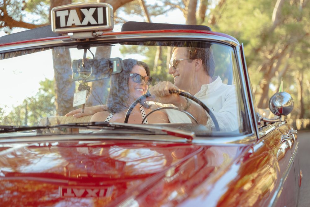 Classic red vintage taxi car driving through scenic coastal road.