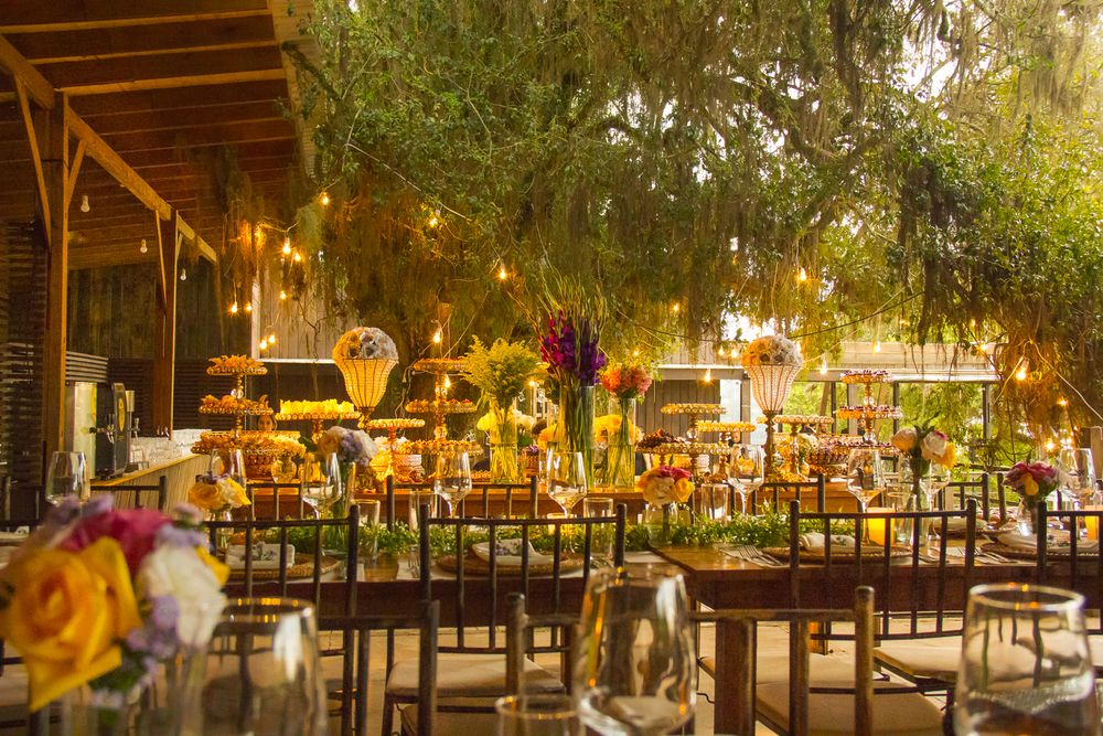Outdoor wedding reception venue lit with warm ambient lighting and decorated tables.