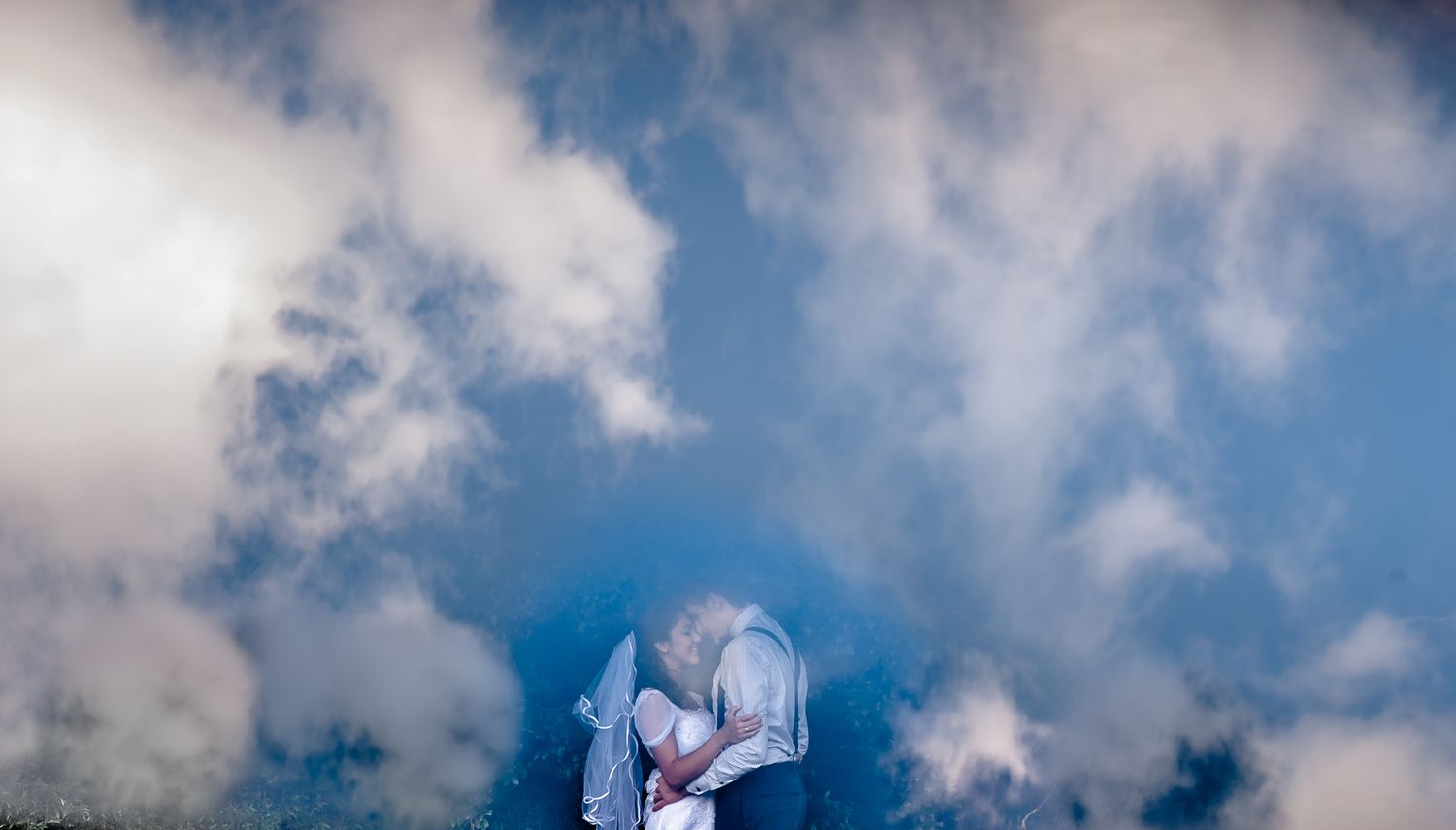 A dreamy wedding portrait framed by dramatic clouds and sky.