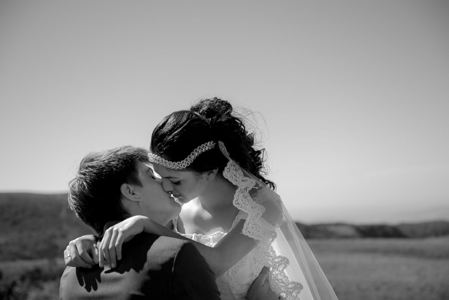 A tender embrace under golden sunlight in an outdoor wedding setting.