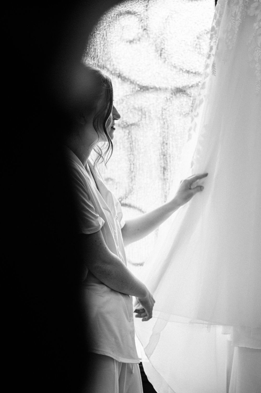 A silhouetted figure stands by a window creating a dreamy, ethereal atmosphere bridal getting ready at Clisby Pines