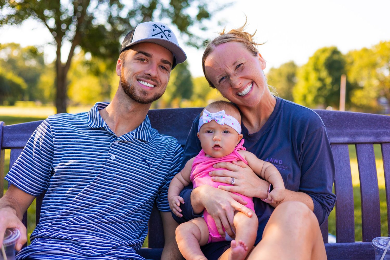Happy family enjoying a sunny day together on a park bench outdoors.