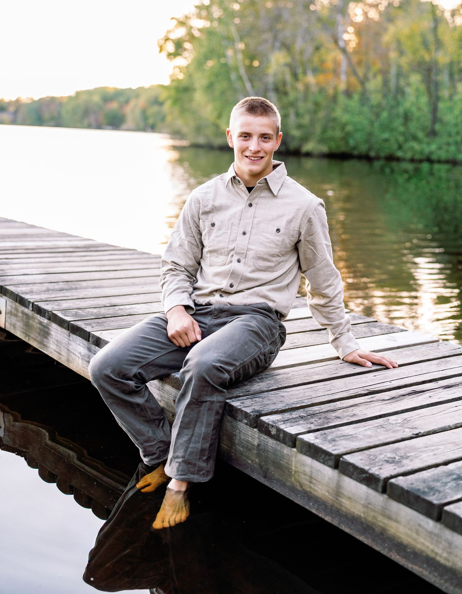 Senior portrait session on wooden dock during golden hour by the lake.