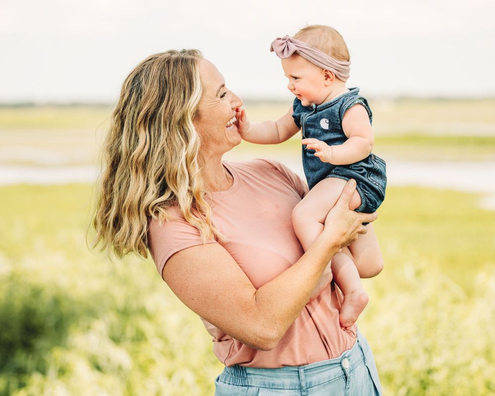 A tender moment between parent and baby in a sunny field.