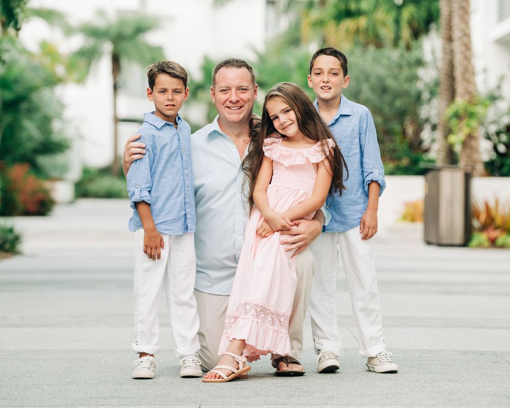 Family members pose together outdoors in coordinating blue and peach outfits during a springtime photoshoot.