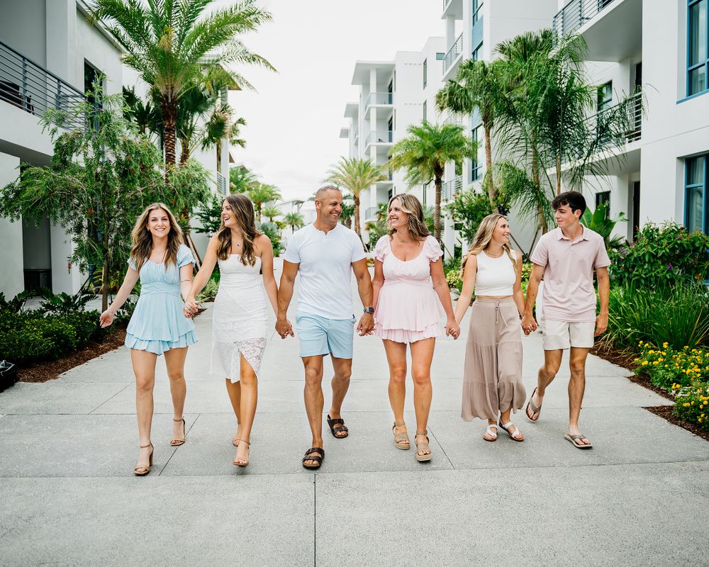 A group walks together down a palm-lined path in light summer outfits.