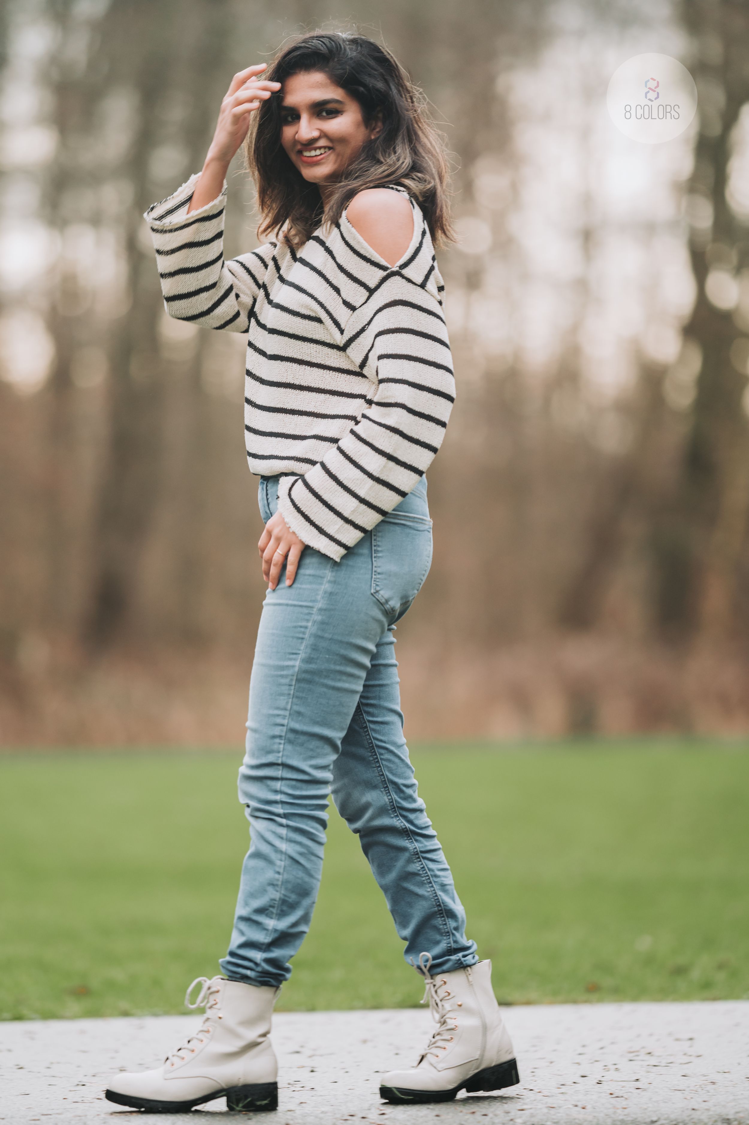 A casual outfit featuring a striped sweater, light blue jeans and beige combat boots in an outdoor setting.