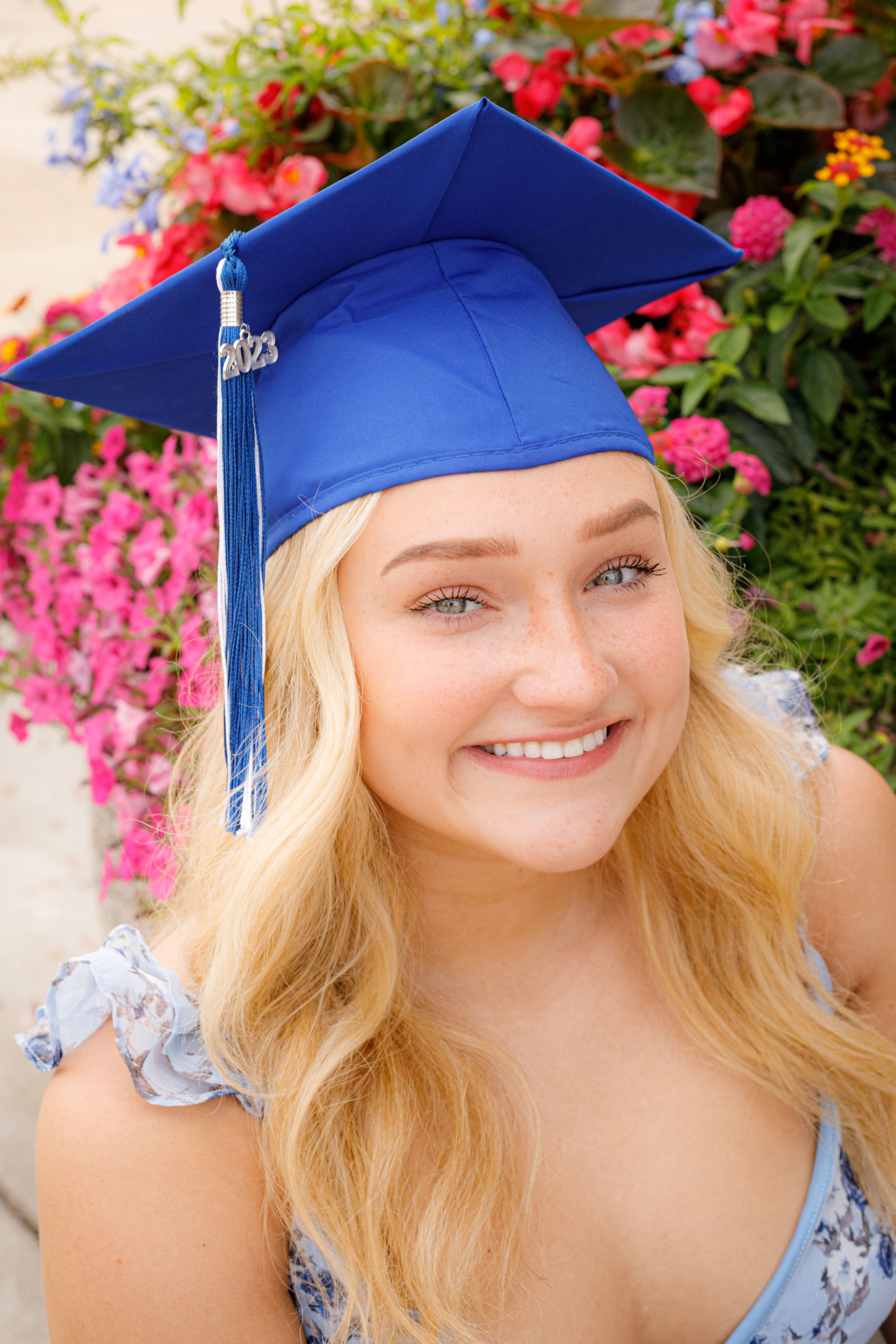 Close-up graduation photos featuring a blue cap and bright pink floral background.