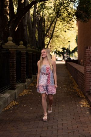 Fashion poses on a brick pathway with wrought iron fencing and autumn trees.