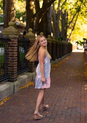 Autumn fashion shoot on a brick-lined path with trees and fallen leaves.