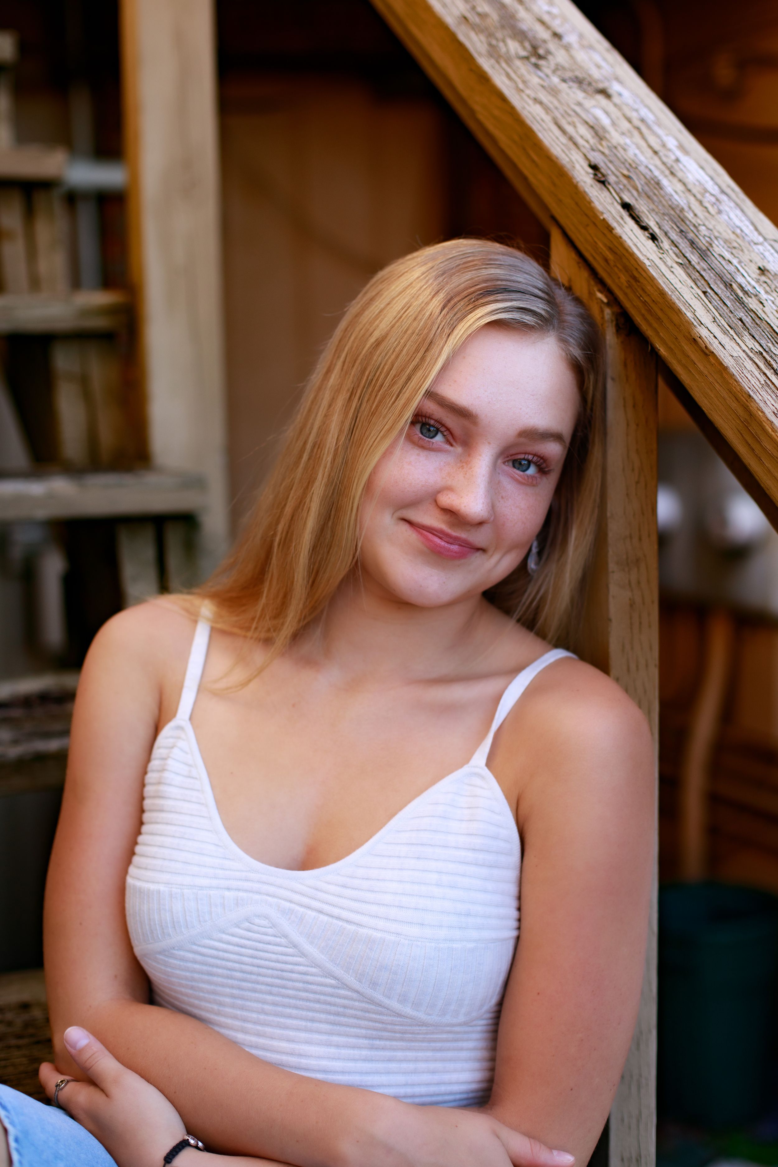 Portrait session on wooden stairs with natural lighting and white top.